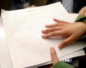 manos tocando papel braille