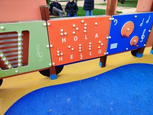 parque infantil con la palabra hola en inglés y  Braille