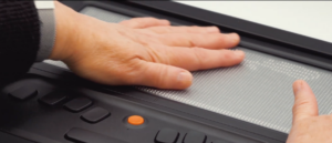 Unas manos deslizandose sobre la pantalla de una línea braille.
